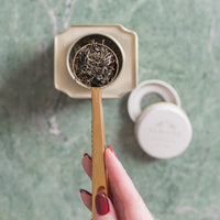 scoop of loose leaf tea over signature caddy